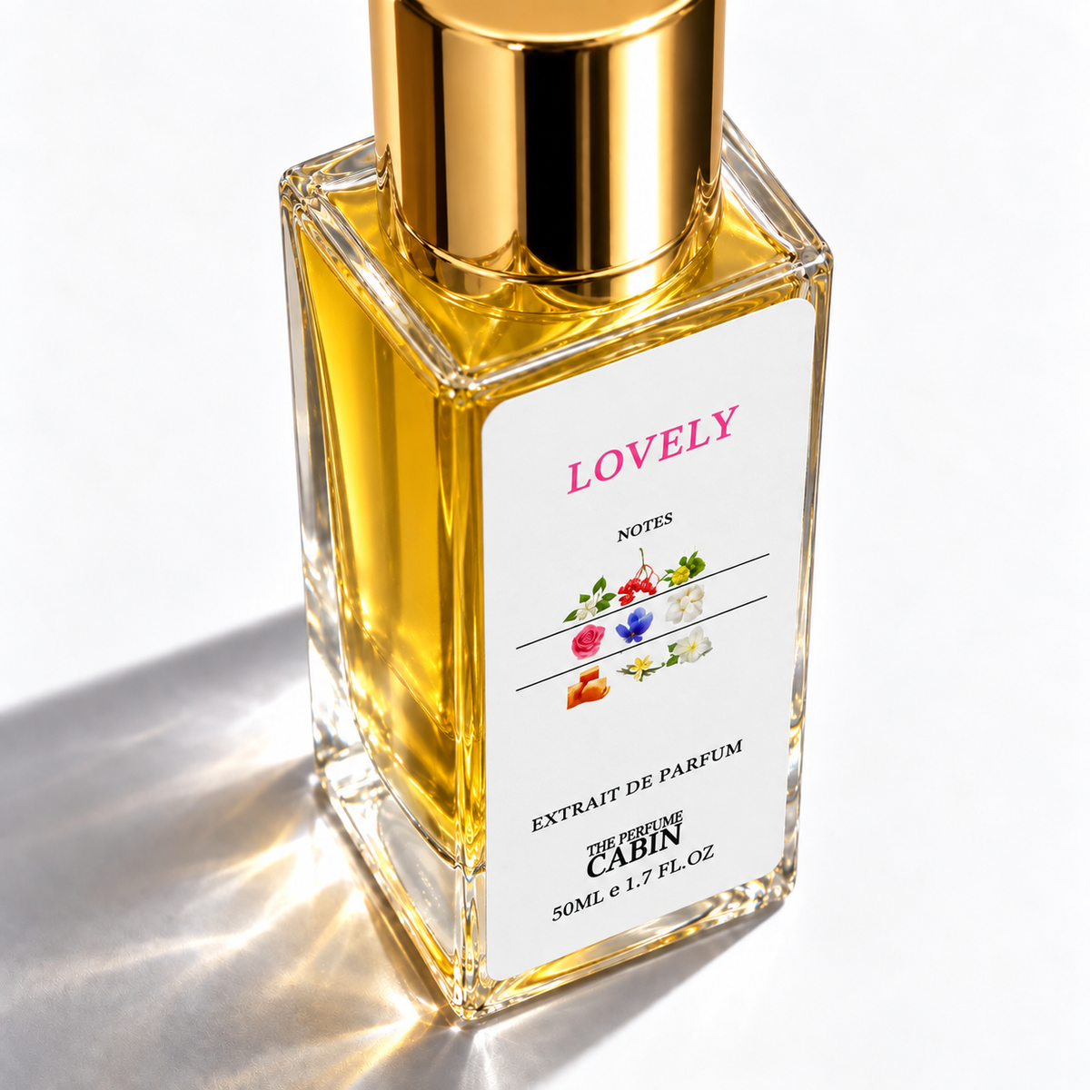 A square glass bottle of 'LOVELY' Extrait de Parfum by The Dream Cabin, filled with golden-yellow liquid and topped with a shiny gold cap, set against a bright white background with soft, warm sunlight and shadows.